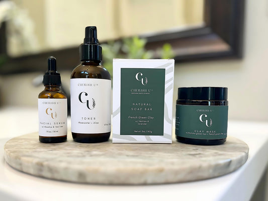 A clarifying skincare set featuring a French green clay soap with tea tree and lavender, matcha green tea + French green clay mask, rosewater + aloe toner, and facial serum with rosehip and tea tree oil on a bathroom vanity. Cherish U®