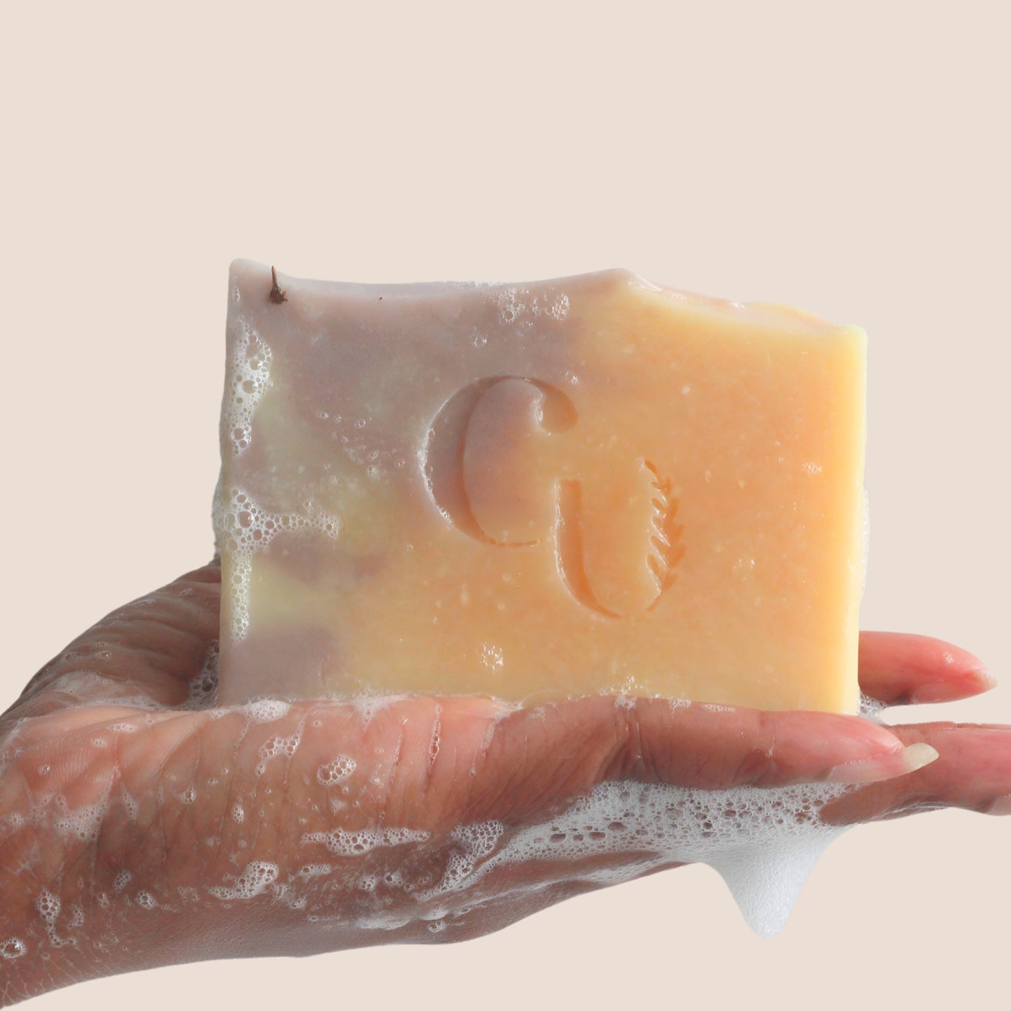 A soapy hand holding a bar of Lavender + Rosemary Citrus soap, lathering up with a rich, foamy texture Cherish U®