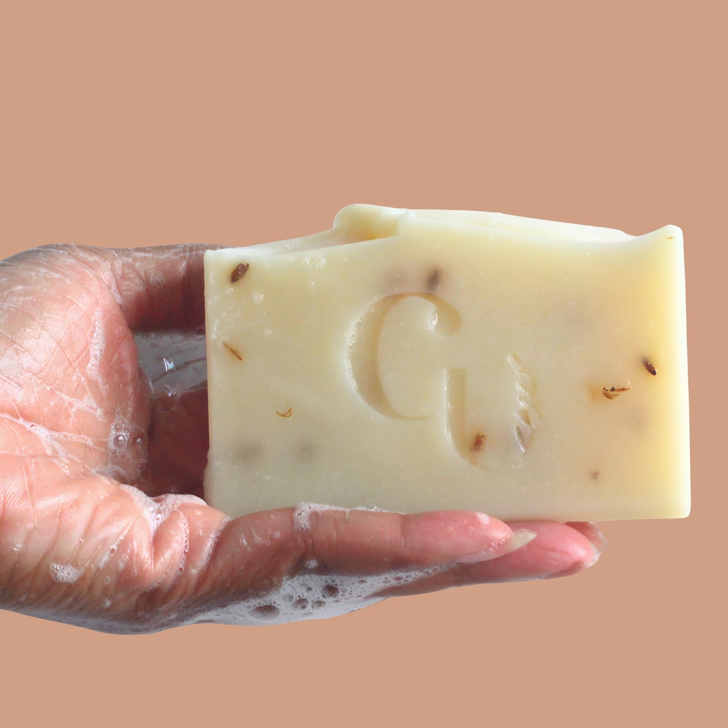 A soapy hand holding a bar of Coconut Shea soap, covered in creamy lather, hinting at deep hydration Cherish U®