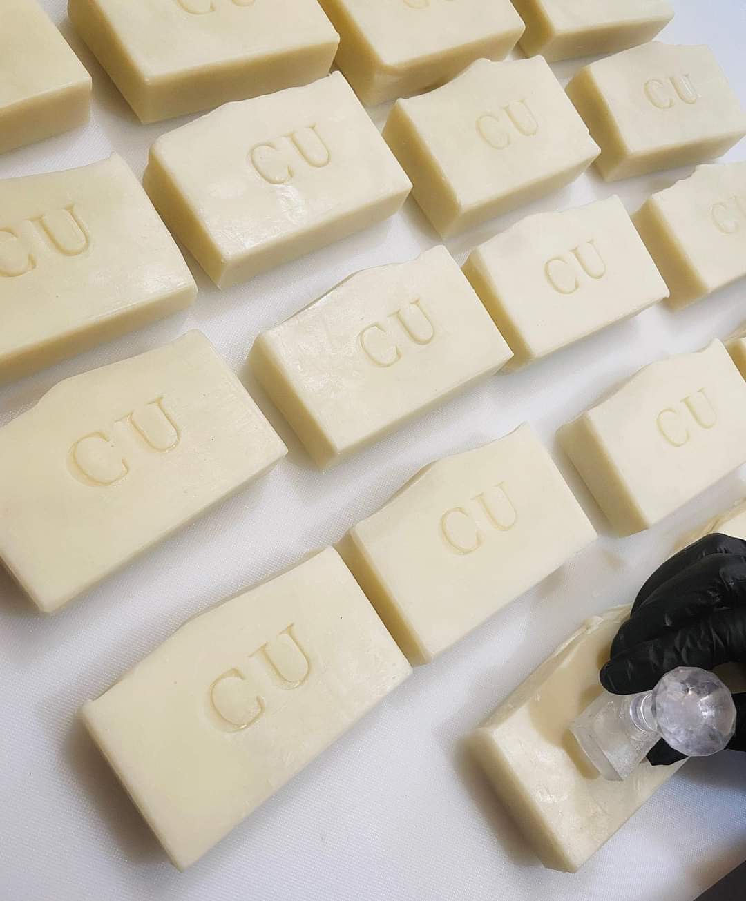 Grid of natural soap being hand stamped with logo