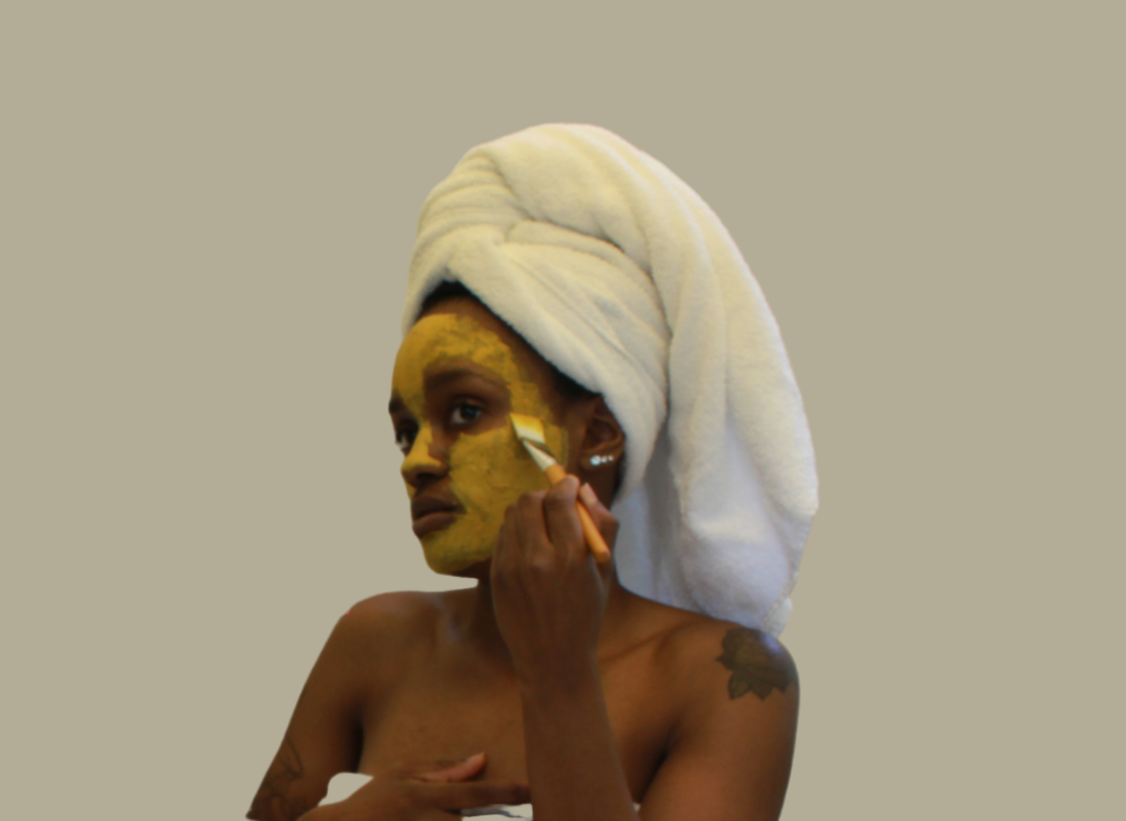 African American female applying Turmeric & kaolin clay facial mask to face