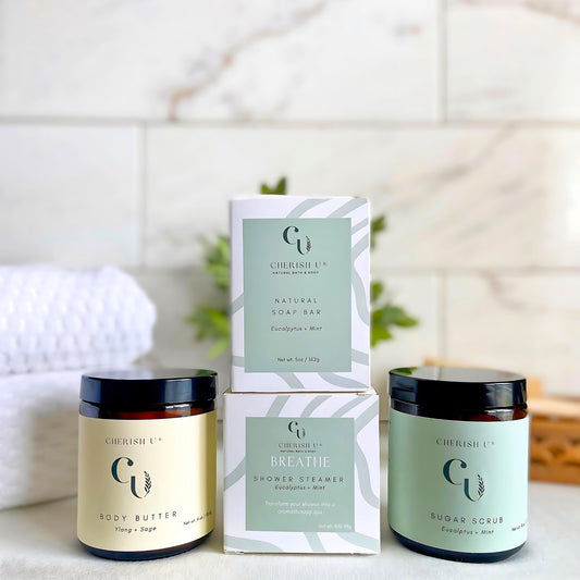 A spa shower gift set featuring Eucalyptus + Mint soap and shower steamer, Ylang + Sage body butter, and Eucalyptus + Mint sugar scrub for a refreshing and rejuvenating experience. Cherish U®