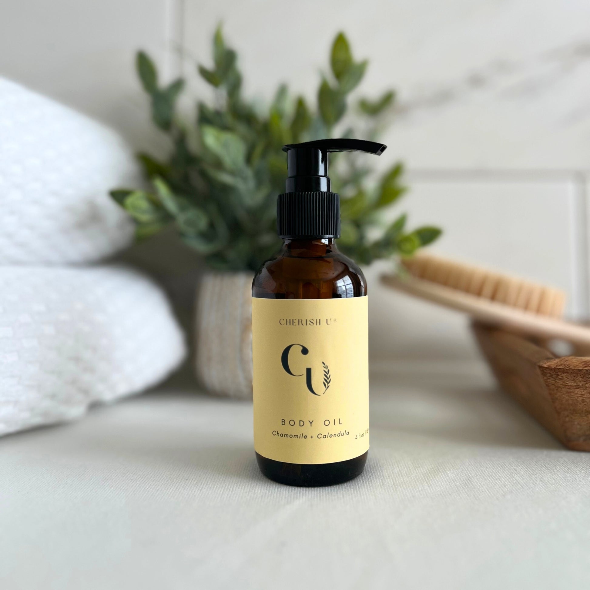 An amber bottle of Chamomile + Calendula body oil with a soothing blend of chamomile and calendula extracts. The bottle features a convenient pump