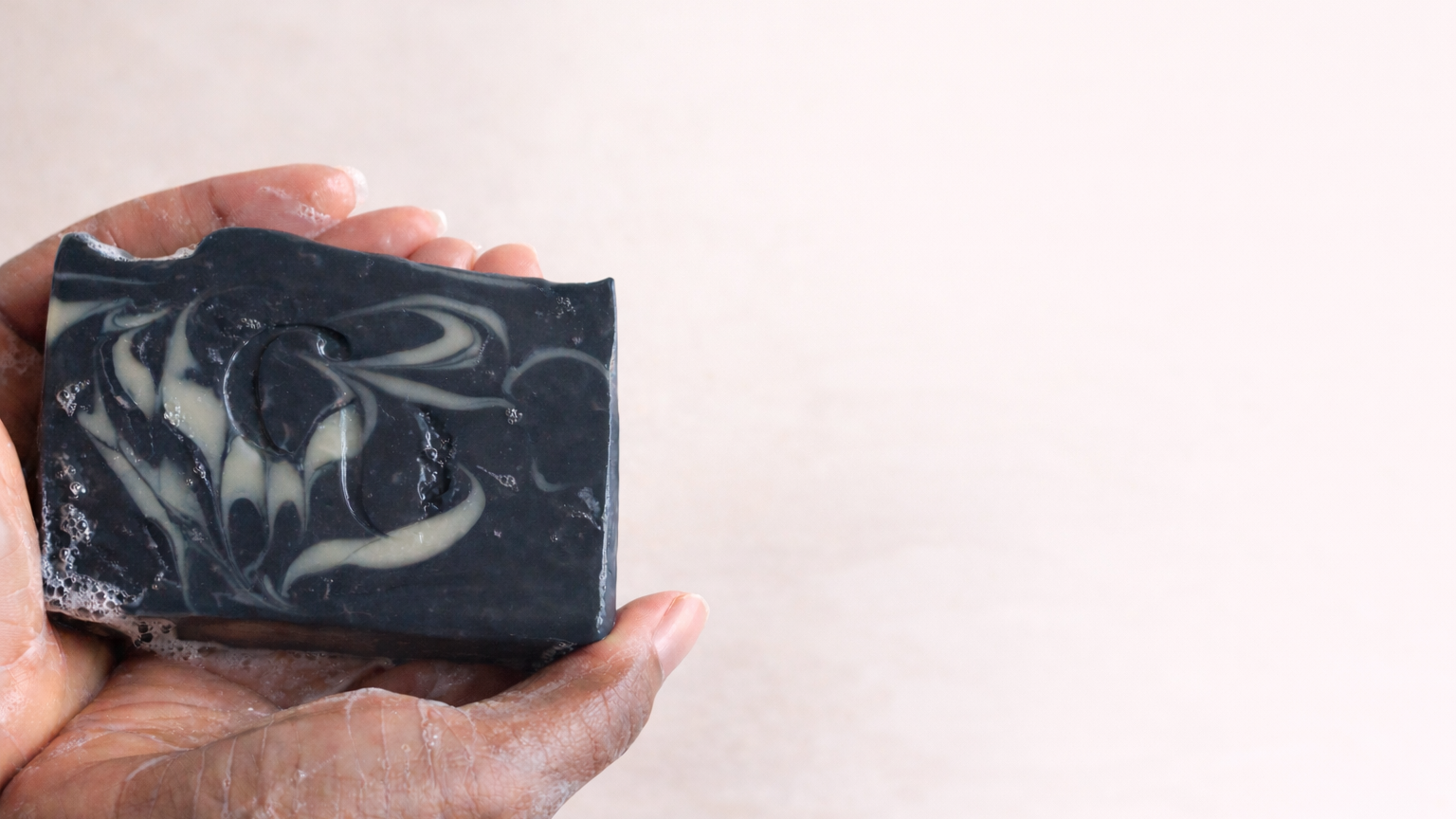 Handcrafted charcoal peppermint soap held in hands, natural soap bar for everyday skin care