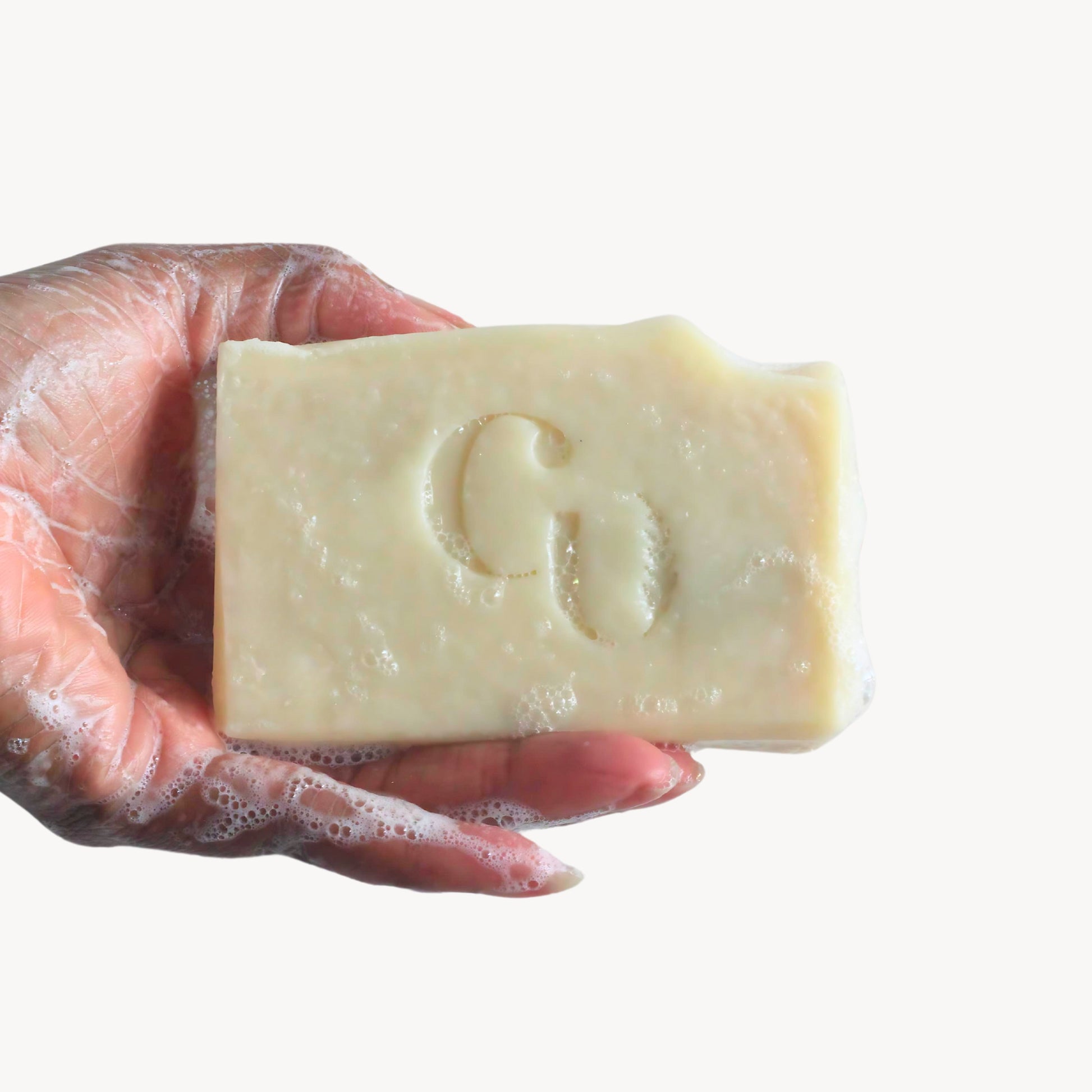 A soapy hand holding a bar of Eucalyptus + Mint soap, generating a cooling, minty lather with hints of eucalyptus