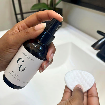 A person applying Rosewater + Aloe Facial Toner with a cotton pad, preparing to gently sweeping it across the face for a soothing and hydrating effect